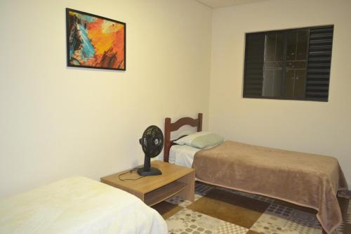 a room with two beds and a clock on a table at Seu lugar na Mantiqueira é aqui! Seja bem-vindo! in Itanhandu