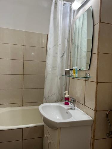 un bagno con un lavandino, uno specchio e una vasca di Boulevard Serenity Apartment a Miercurea-Ciuc