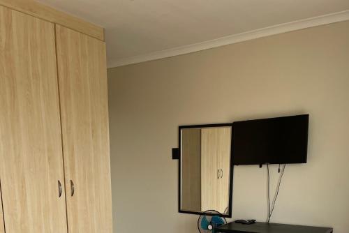 a bedroom with a mirror and a tv on the wall at Private Rooms - home-stay in Gqeberha