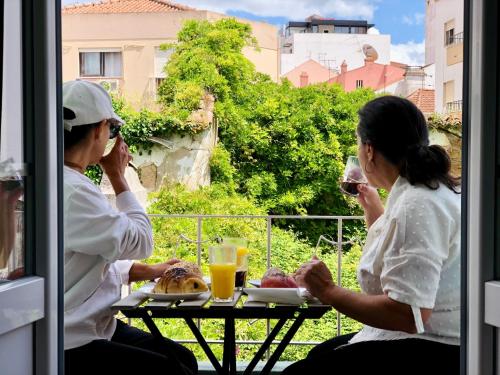 two people sitting at a table with food and drinks at Design no centro histórico a 30 min Lisboa in Torres Vedras