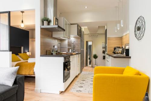 un salon avec une chaise jaune et une cuisine dans l'établissement Unsejouranantes - Le Magellan, à Nantes