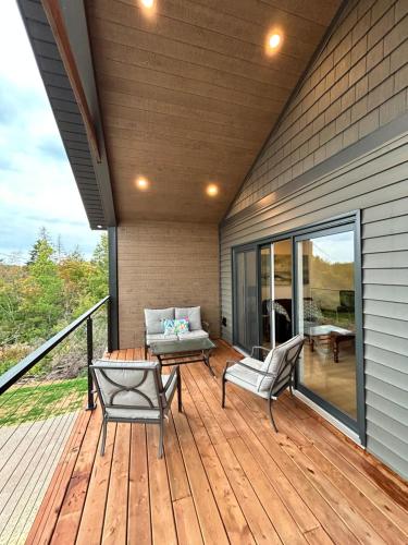 a wooden deck with two chairs and a couch at Garagemahal on Glengyle in Milton Station