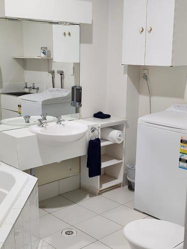 a white bathroom with a sink and a toilet at U Studios Paraparaumu, SureStay Collection by BW in Paraparaumu Beach