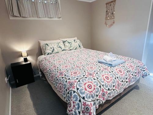 a bedroom with a bed with a red and white comforter at Large 1BR Suite and Private Lounge in Tauranga