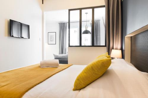 Dormitorio con cama con almohada amarilla en Unsejouranantes - Le Magellan, en Nantes