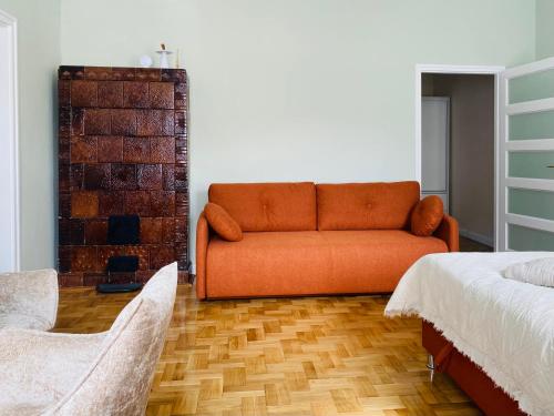 an orange couch in a living room with two beds at Patak & Stone apartman in Szentendre