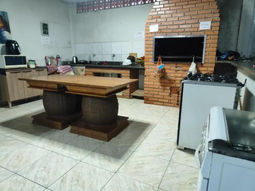 een keuken met een houten tafel en een bakstenen oven bij Quarto casal in Cianorte