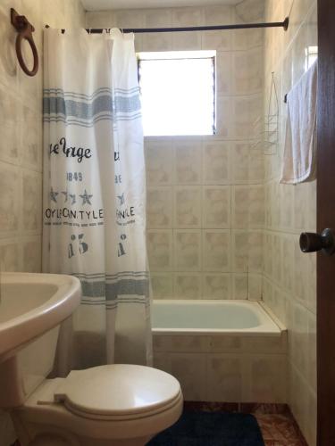 a bathroom with a toilet and a tub and a shower curtain at Chalet Bordemar in Concón