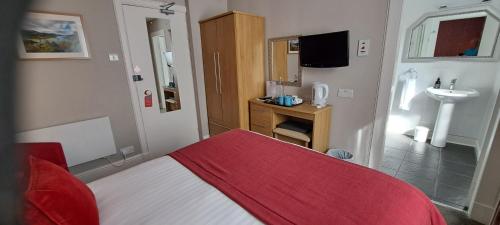 a bedroom with a bed with a red blanket and a sink at Derrybeg Bed and Breakfast in Pitlochry