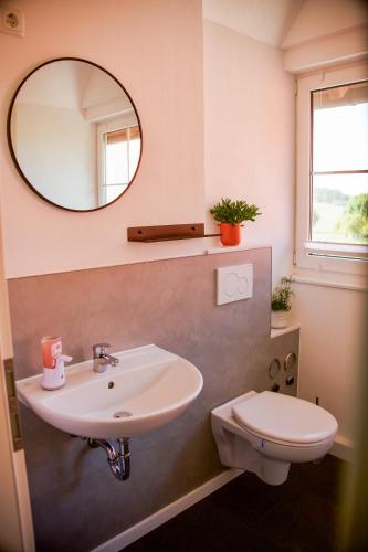 a bathroom with a sink and a toilet and a mirror at Ferienwohnung Peters in Hünfeld