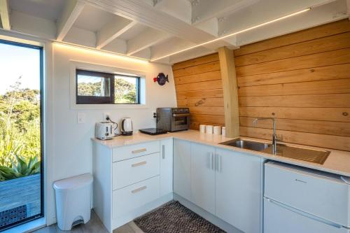 a kitchen with white cabinets and a sink and a window at Perch on the Ridge by Waiheke Pure in Waiheke Island
