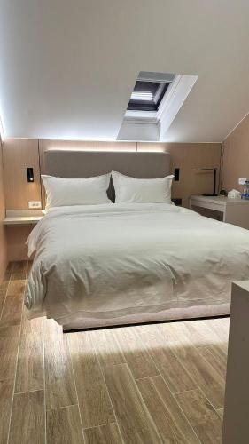 a bedroom with a large white bed with a skylight at KIMMIY Garni Attic Rooms near Belgrade Airport in Beograd