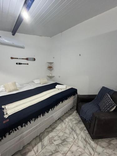 a bedroom with a large bed and a chair at Suites a 5min da Broadway in Aracati