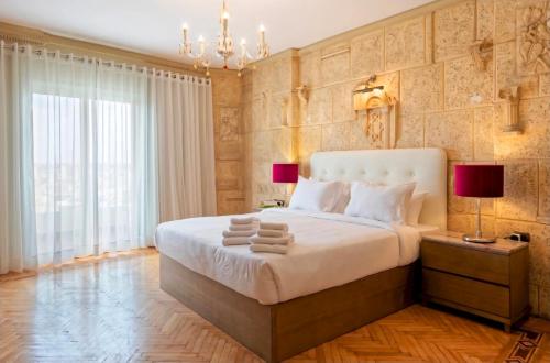 a bedroom with a large bed and a chandelier at Zamalek Nile View in Cairo