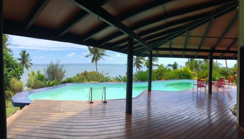 uma piscina com um deque de madeira com vista para o oceano em Garden Of Eden em Matei