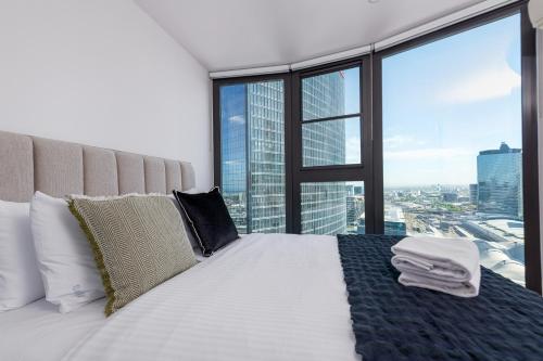 a bedroom with a white bed with a large window at Flinders St Central - Parking, Gym, Pool & Sauna in Melbourne