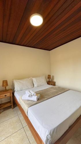 a bedroom with a white bed with a wooden ceiling at GO Hotelaria in Búzios