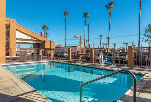 a swimming pool in a parking lot with palm trees at Days Inn by Wyndham Chula Vista-San Diego in Chula Vista