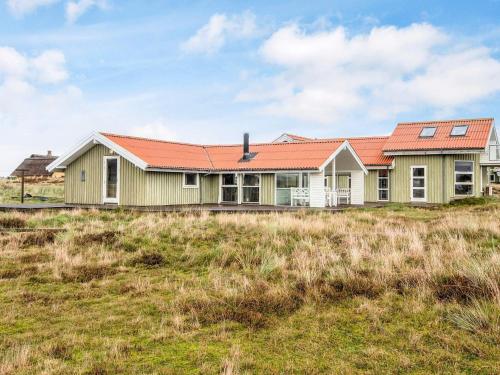 a green house with an orange roof on a field at 4 star holiday home in Fanø in Fanø
