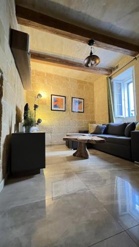 a living room with a couch and a table at De Rohan Central Townhouse 38 in Taʼ l-Infetti