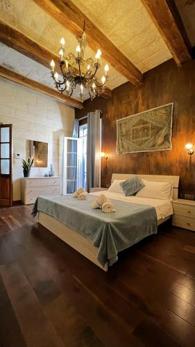 a bedroom with a large bed and a chandelier at De Rohan Central Townhouse 38 in Taʼ l-Infetti