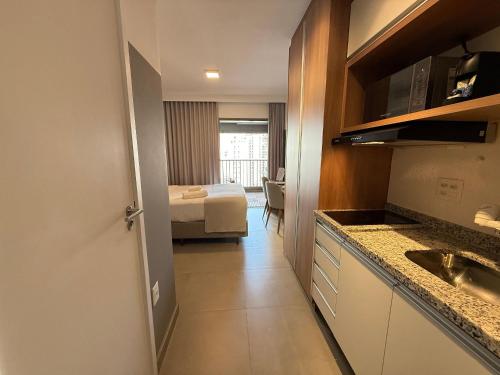 a room with a kitchen and a bedroom with a bed at On Jurupis in Sao Paulo