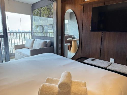 a bedroom with a bed and a couch and a tv at On Jurupis in Sao Paulo