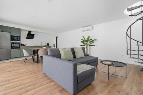 a living room with a gray couch and a kitchen at Ermal Terrace in Vieira do Minho