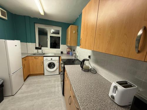 a kitchen with a refrigerator and a washer and dryer at Rest & Recover in Wednesbury