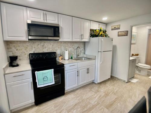 Una cocina con gabinetes blancos y una estufa negra. en Loving Apartment! 5 min from the beach in car, en Clearwater