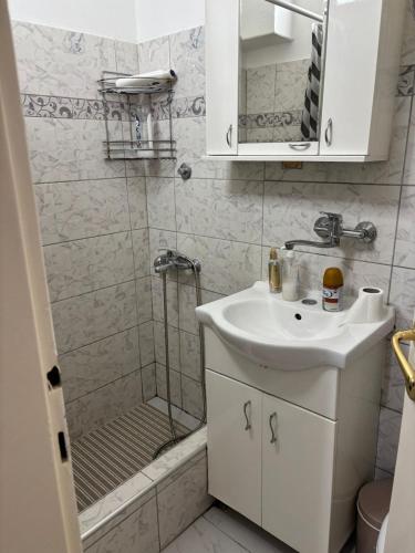 a white bathroom with a sink and a shower at Apartman Zaki luxury in Borča