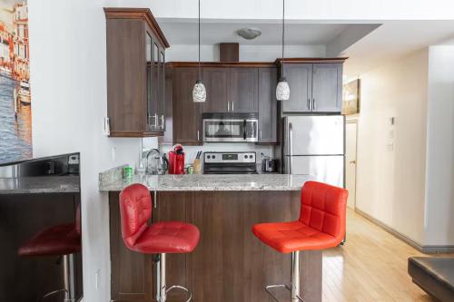 a kitchen with two red bar stools and a refrigerator at Suitestay Apartments Hotel in Ottawa