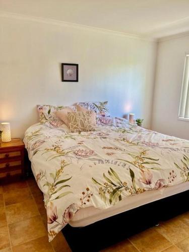 a bedroom with a bed with a floral comforter at 71 The Esplanade in Woodgate