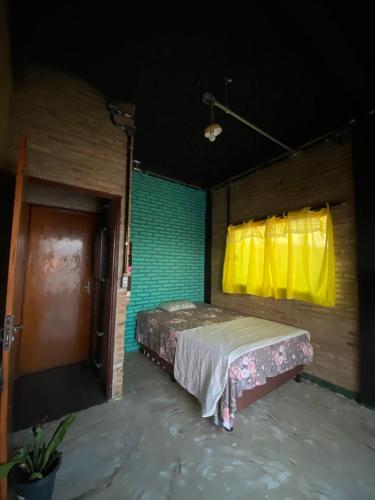 a bedroom with a bed and a yellow window at Fabulosa Casa de tijolinho in Arapiraca