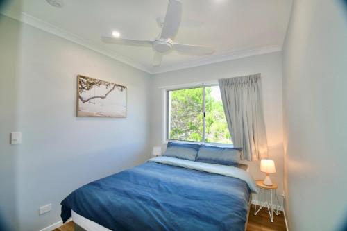 a bedroom with a blue bed and a window at 158 The Esplanade in Woodgate