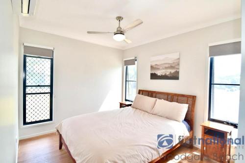 a bedroom with a bed and two windows at 62 First Avenue in Woodgate