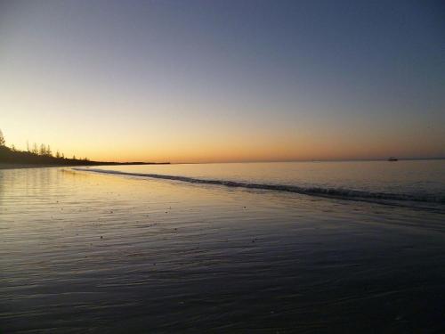 a sunset on a beach with the ocean at 198 The Esplanade in Woodgate