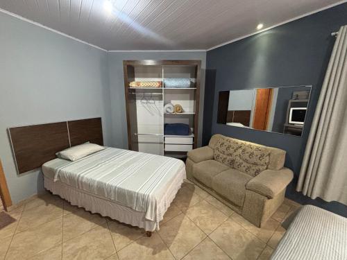 een slaapkamer met een bed en een bank bij Suite/loft Jardim Botanico in Curitiba