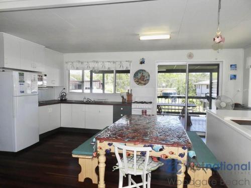 uma cozinha com uma mesa e duas cadeiras e um balcão em 25 Walkers Point Esplanade em Burrum Heads