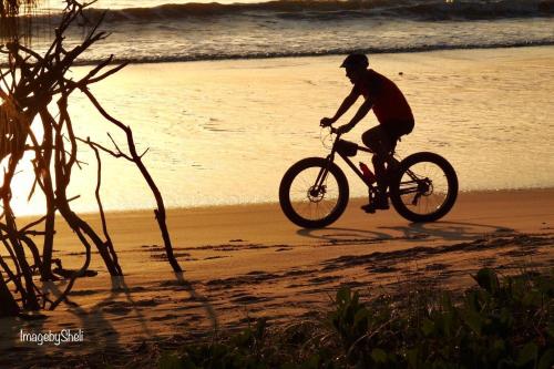 um homem a andar de bicicleta na praia em 25 Walkers Point Esplanade em Burrum Heads