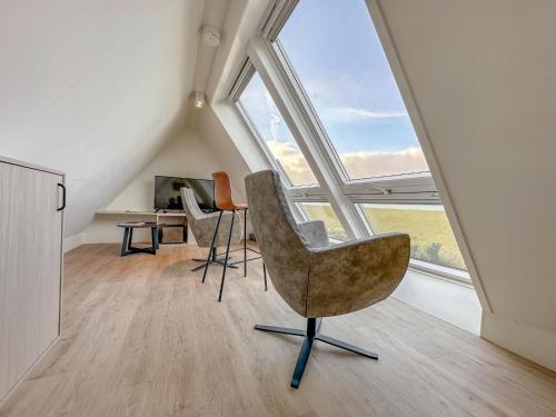 a room with an attic with windows and a chair at Happy Beach 48 in Colijnsplaat