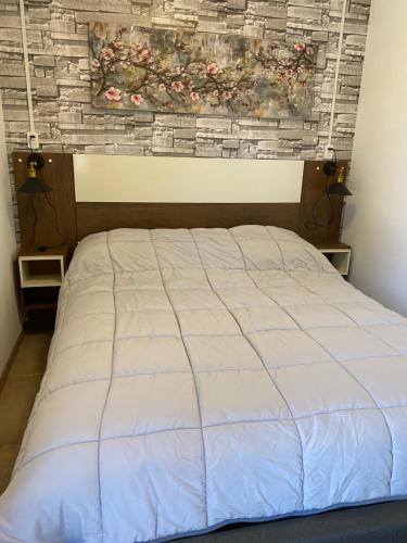 a bed in a bedroom with a brick wall at Cabaña con quincho, tinaja y piscina in Coinco