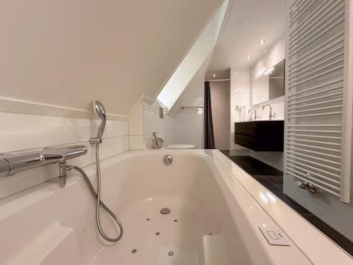 a white bath tub with a shower in a bathroom at Happy Beach 50 in Colijnsplaat