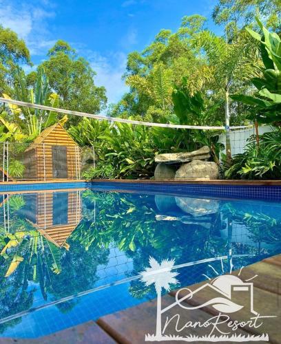 a swimming pool in front of a house with trees at Nano Resort in Porangaba
