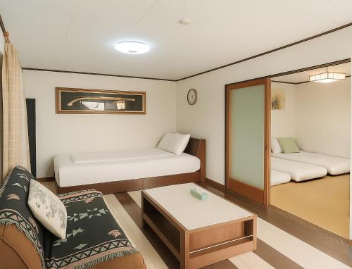 a small room with two beds and a couch at Nippori Osaka Nishi-Tengachaya Guesthouse西天下茶屋アパートメント in Osaka