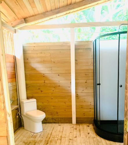 a bathroom with a toilet in a wooden wall at Una Habitación baño privado Casa Mango in Zapzurro