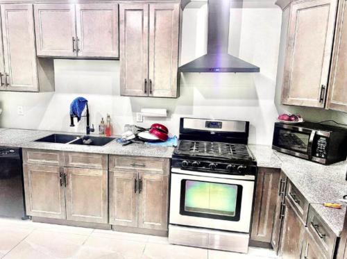 een keuken met houten kasten en een kookplaat met oven bij Private Room In Cambridge B13 in Cambridge