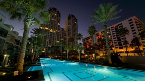 a swimming pool with palm trees and buildings at night at Penthouse Jr Unrivaled Luxury Insane Views apts in South Padre Island