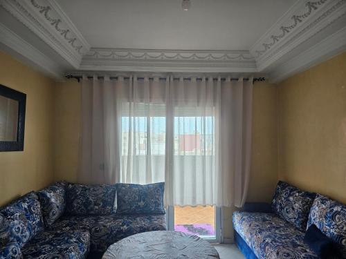 a living room with a couch and a large window at Appartement famille plage in El Jadida