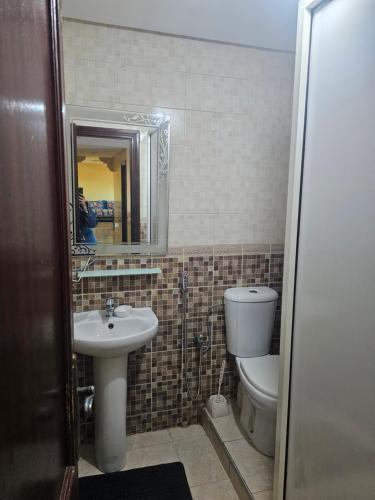 a bathroom with a sink and a toilet and a mirror at Appartement famille plage in El Jadida